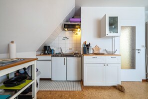 Eine kompakte Küche mit weißen Schränken, einer kleinen Arbeitsfläche und einer gefliesten Spritzschutzwand.