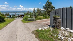 A paved pathway leading to a building with solar panels, a bench, and a tree stump with a bowl. - Holiday Home 'Stauseeblick' with Lake View, Private Terrace and Wi-Fi (Kelbra)