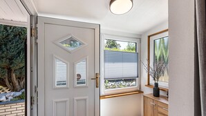 A hallway with a white door, a window with blinds, a wooden cabinet, and a framed picture on the wall. - Holiday Home 'Stauseeblick' with Lake View, Private Terrace and Wi-Fi (Kelbra)