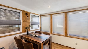 A dining area with a wooden table, chairs, and large windows with blinds. - Holiday Home 'Stauseeblick' with Lake View, Private Terrace and Wi-Fi (Kelbra)
