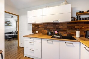 Eine moderne Küche mit weißen Schränken, einer Holzrückwand und einem schwarzen Spülbecken.