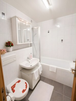 Ein modernes Badezimmer mit Toilette, Waschbecken, Dusche und Badewanne.