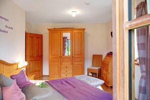 A bedroom with a bed, a wooden wardrobe, a chair, and a dresser.