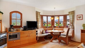 A kitchen with a stove, oven, microwave, and a television. There is a dining area with a table and chairs. - Apartment 'Landhaus Bergkulisse' with Mountain View, Shared Terrace and Wi-Fi (Wallgau)