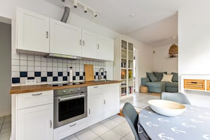 A modern kitchen with white cabinets, a tiled backsplash, and a wooden countertop.