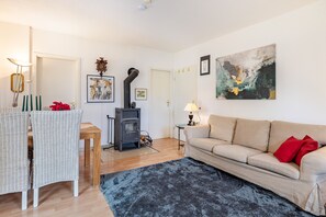 A living room with a sofa, a dining table with chairs, a fireplace, and artwork on the walls.