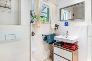 A bathroom with a white sink, a mirror, a towel rack, and a window with curtains.