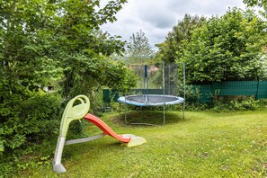A trampoline surrounded by a green fence and dense foliage. - Holiday Home 'Christina' with Private Sauna, Terrace, and Garden (Löffingen)