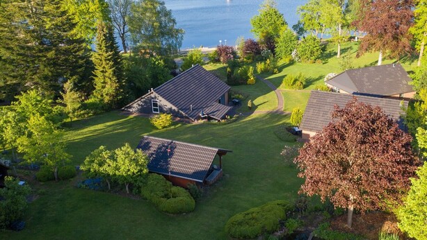 A residential area with houses, a lawn, and a body of water. - Holiday Home 'Eiderblick' with Private Terrace, Private Garden and Wi-Fi (Borgstedt)