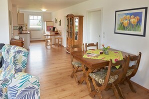 A dining area with a wooden table, chairs, and a cabinet. - Holiday Home 'Eiderblick' with Private Terrace, Private Garden and Wi-Fi (Borgstedt)