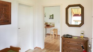 A hallway with a wooden bench, a dresser with a mirror, and a door leading to a kitchen area. - Holiday Home 'Eiderblick' with Private Terrace, Private Garden and Wi-Fi (Borgstedt)