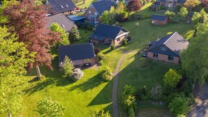 An aerial view of a residential area with houses, green lawns, and a winding path. - Holiday Home 'Eiderblick' with Private Terrace, Private Garden and Wi-Fi (Borgstedt)