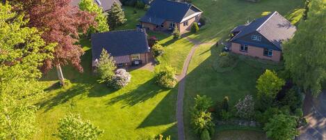 An aerial view of a residential area with houses, green lawns, and a winding path.