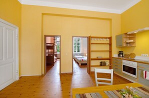 Eine kleine Küche mit Holzausstattung, einem Esstisch und Blick in ein Schlafzimmer.