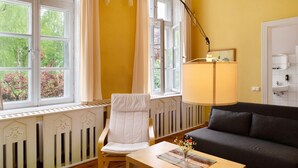 Een kamer met een radiator, een stoel, een tafel met een vaas, een lamp en een bank.