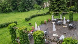 A patio area with tables and chairs, surrounded by greenery and a swing set. - Studio Apartment 'Ferienwohnung 3' with Shared Terrace, Shared Garden (Krakow am See)
