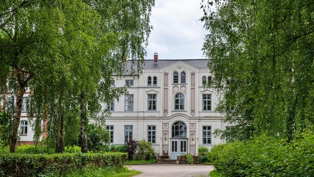 A large, historic building with a symmetrical facade, arched windows, and a central entrance with a door. - Studio Apartment 'Ferienwohnung 3' with Shared Terrace, Shared Garden (Krakow am See)