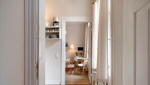 A narrow hallway with a dining area at the end, featuring a table, chairs, and a lamp. - Studio Apartment 'Ferienwohnung 3' with Shared Terrace, Shared Garden (Krakow am See)
