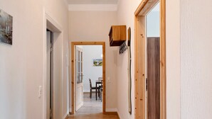 A hallway with wooden flooring, white walls, and a dining area in the background. - Apartment 'Ferienwohnung 5' with Shared Terrace, Shared Garden (Krakow am See)