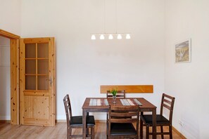 Un coin repas comprenant une table en bois, quatre chaises, un banc et un luminaire suspendu.