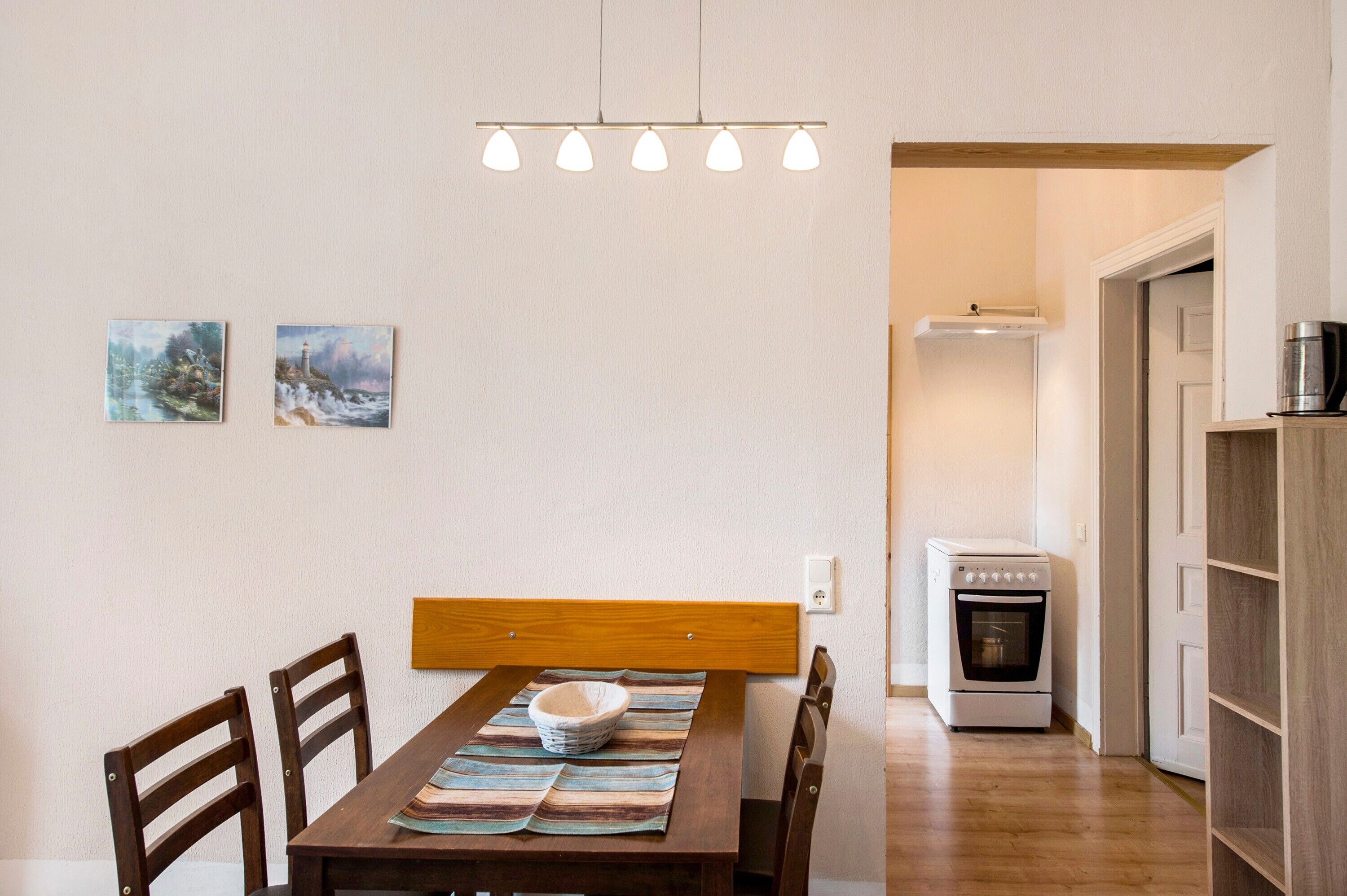 A dining area with a wooden table, chairs, a bowl, and a painting on the wall.