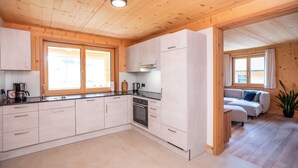 Una cucina moderna con mobili in legno, forno integrato e zona pranzo con divano e pianta in vaso.