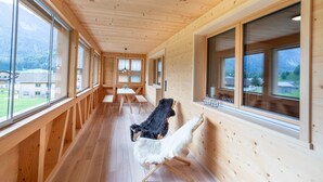 Un interno in legno con ampie finestre, una zona pranzo e vista sull'esterno.