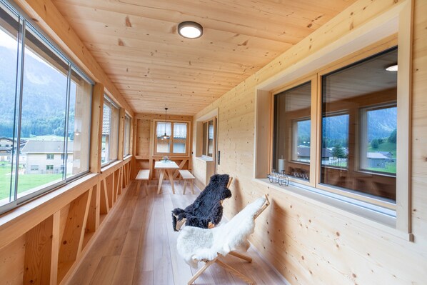 A wooden interior with large windows, a dining area, and a view of the outdoors.