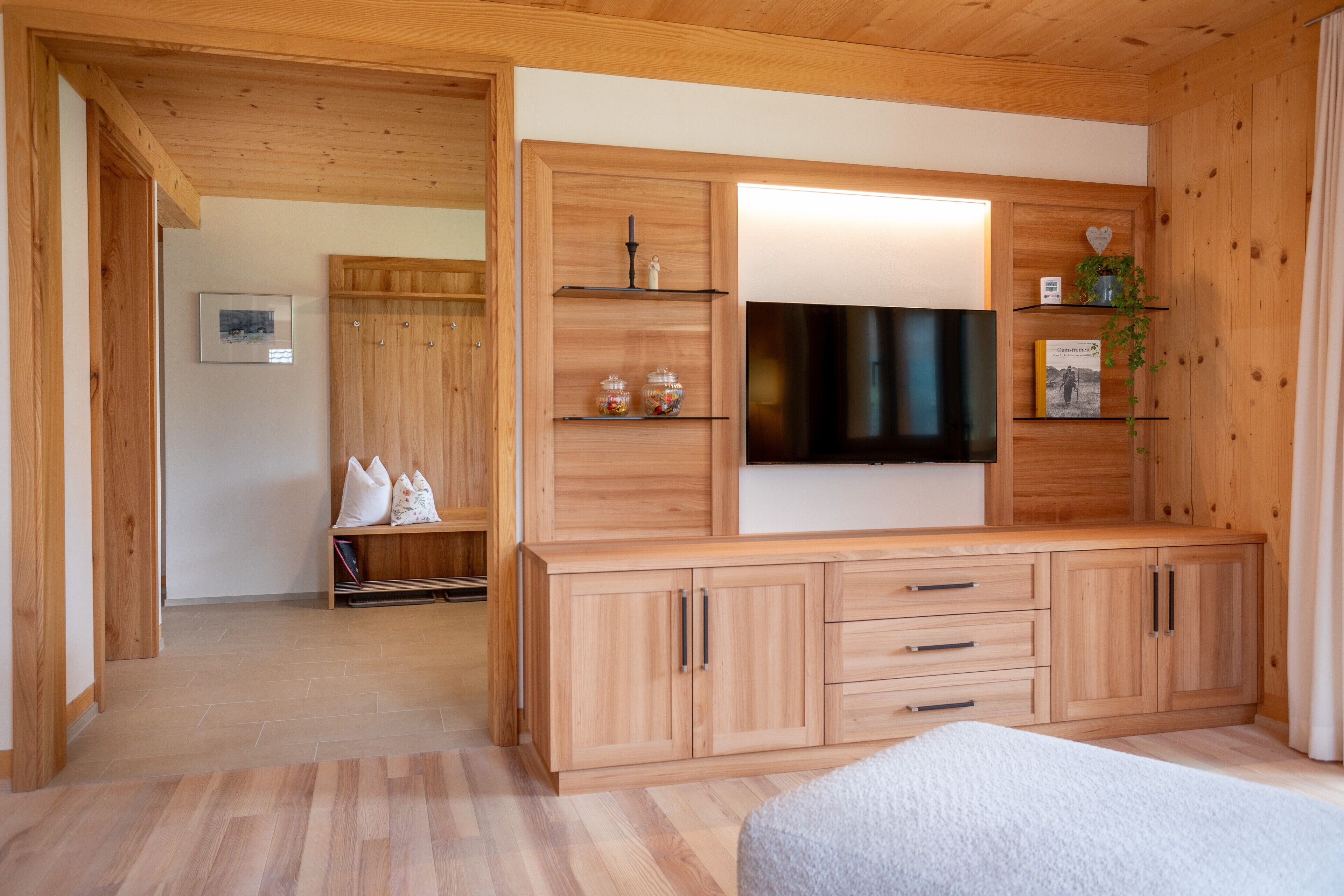 Una habitación con paneles de madera, un televisor, estanterías y una cama.