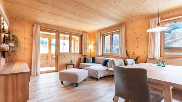 Un interno in legno con un divano, poggiapiedi, tavolo da pranzo e sedie.