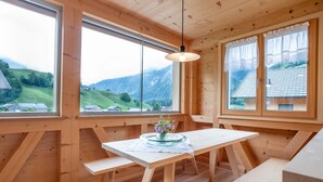 Un interno in legno con ampie finestre, un tavolo con un vaso di fiori e vista su un paesaggio verde.
