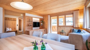 Un interno in legno con un tavolo da pranzo, divani, una televisione e finestre.