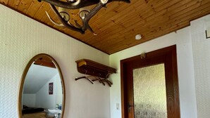 A room with a wooden ceiling, a round mirror, a radiator, a wooden bench, a coat rack, and a textured door. - Apartment 'Fuldawiesen' with Balcony and Wi-Fi (Schlitz)