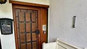 A room with a wooden door, a white bench, a wall-mounted light, and a small mailbox. - Apartment 'Fuldawiesen' with Balcony and Wi-Fi (Schlitz)