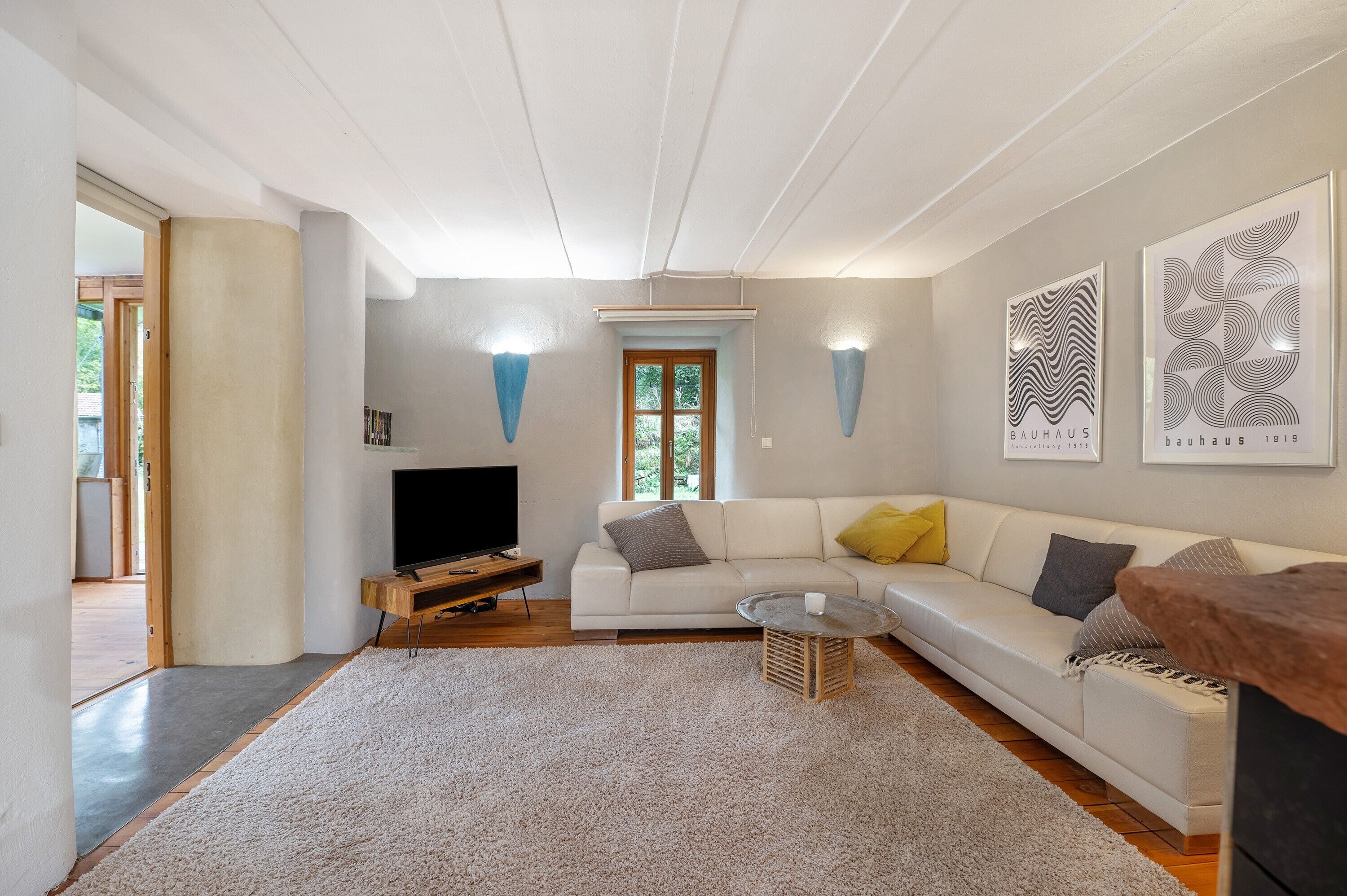 Een moderne woonkamer met een witte bank, een salontafel, een televisie en kunstwerken in lijsten aan de muur.