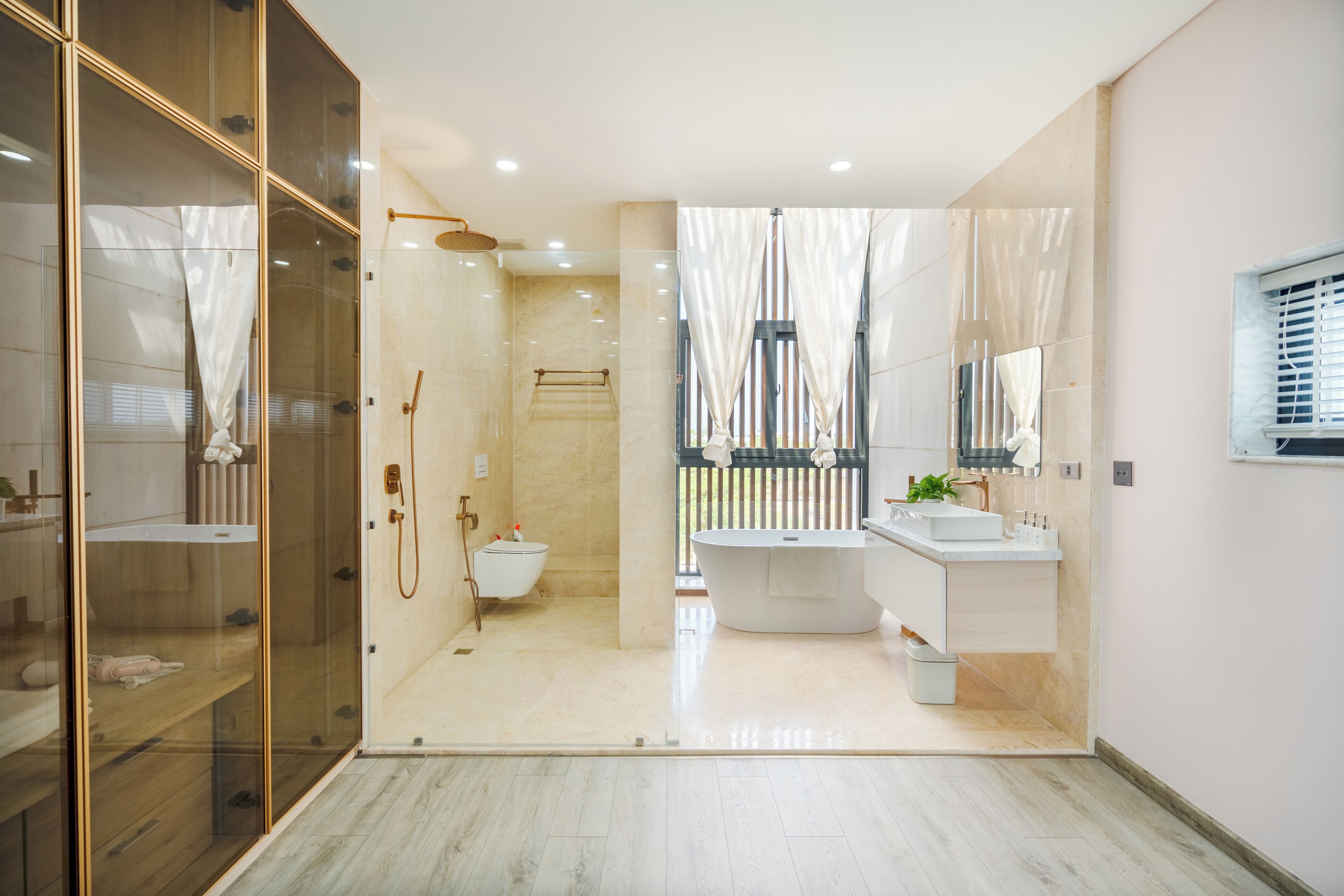 A modern bathroom with a glass shower enclosure, a freestanding bathtub, and a vanity with a mirror.