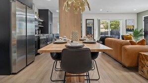 A modern kitchen with a dining table, chairs, and a sofa. - Modern 7BR Triplex | Sleeps 20 | Steps to Beach (North Myrtle Beach)