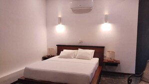Quarto bem arrumado com cama, abajures e ar condicionado.