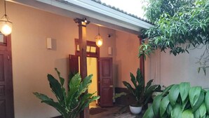 Entrada de um edifício com duas plantas em vasos e luminárias pendentes.