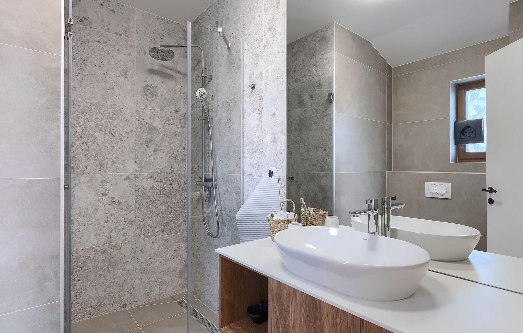 A modern bathroom with a glass-enclosed shower, a white sink, and a large mirror.