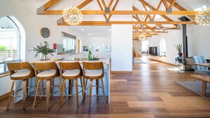 Una cocina amplia con vigas de madera, una isla central con taburetes y vista al área de comedor.