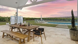 Un patio al aire libre con una mesa y bancos de madera, una piscina y vistas al paisaje.