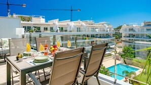 Ein Dachrestaurant mit Tisch für zwei Personen mit Blick auf einen Swimmingpool und moderne Gebäude.