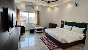 A modern bedroom with a marble floor, a bed with white bedding, a ceiling fan, and a TV mounted on the wall. - Hotel white inn (Haldwani)