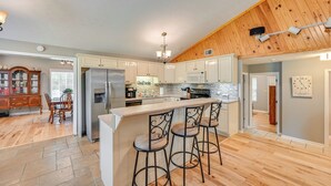 A kitchen with a central island, bar stools, a refrigerator, and a wooden ceiling. - Access to Rough River Lake! Family Home w/ Deck (Leitchfield)