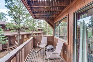 A wooden deck with two rocking chairs and a small table, overlooking a forested area. - Walk to Chair Lift: Angel Fire Condo w/ Mtn Views (Angel Fire)