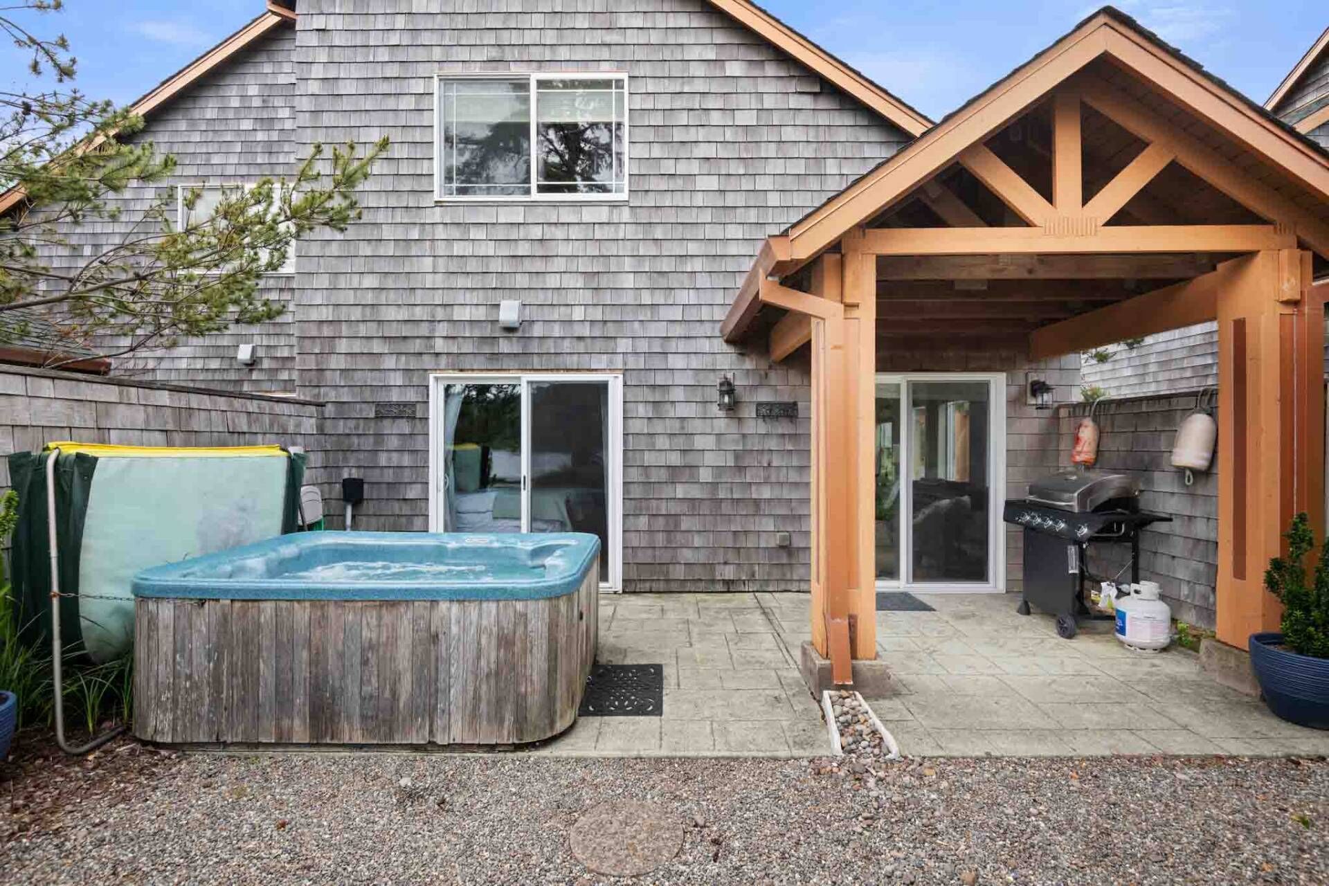 Una casa con un patio techado, un jacuzzi y una zona de barbacoa.