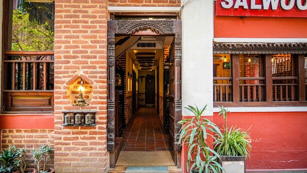 A brick building with a red facade, a wooden door, and a sign that reads "SALWOO". - Hongsi Hotel (Kathmandu)