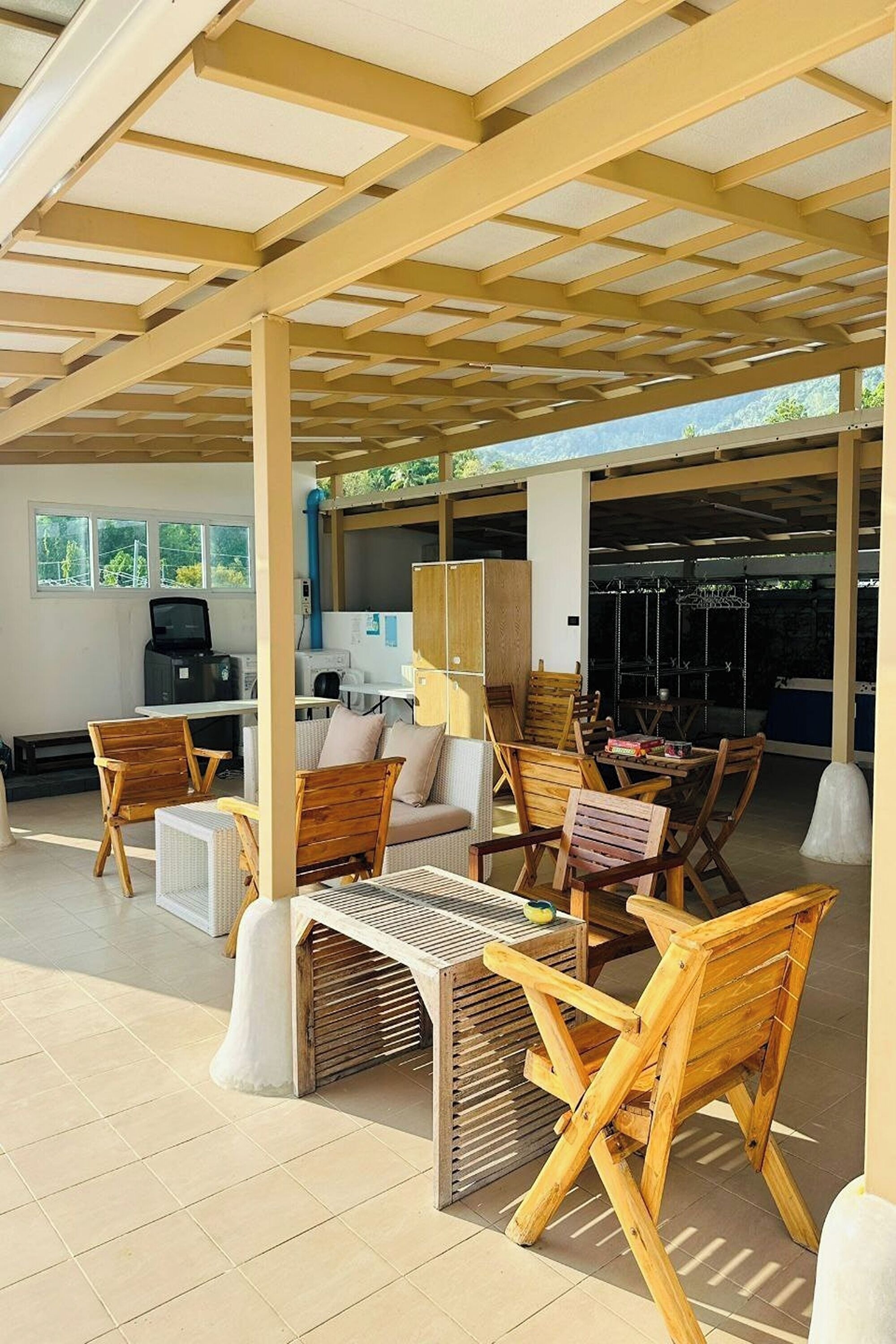 Un patio al aire libre con mobiliario de madera, una parrilla y una zona de estar cubierta.