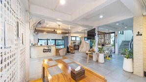 Un interior moderno con un mostrador de recepción, una zona de estar y una escalera que conduce a un nivel superior.